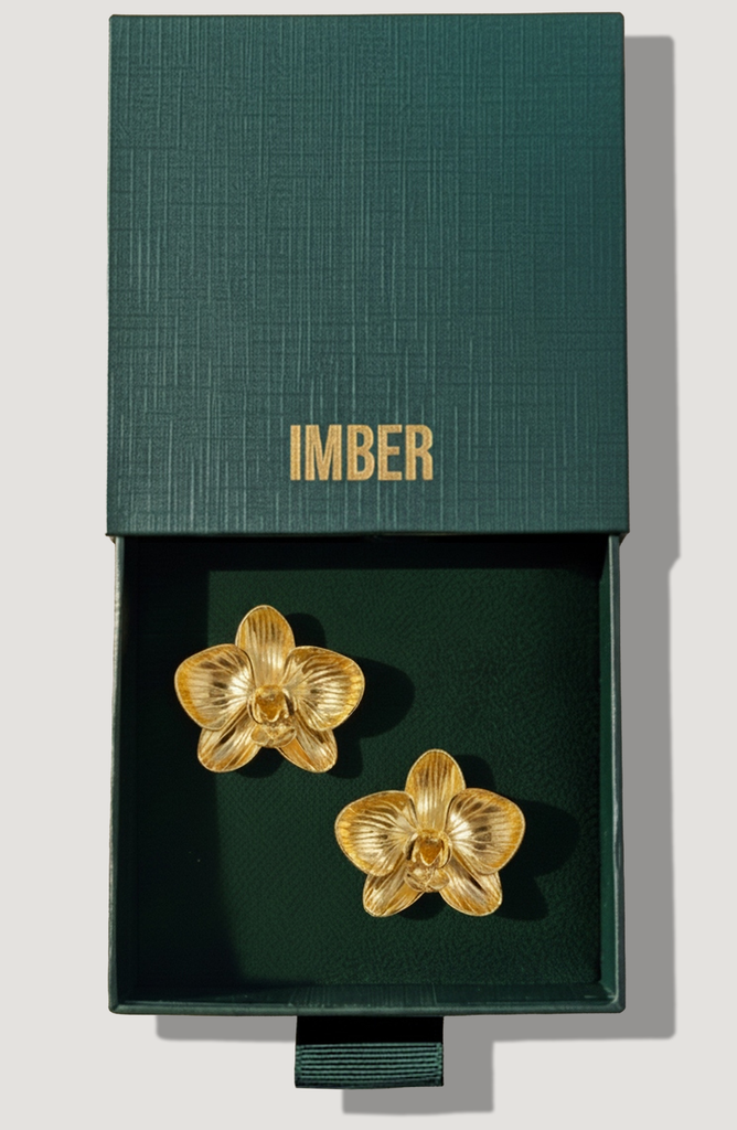 IMBER Orchid gold flower stud earrings in open green gift box, top view