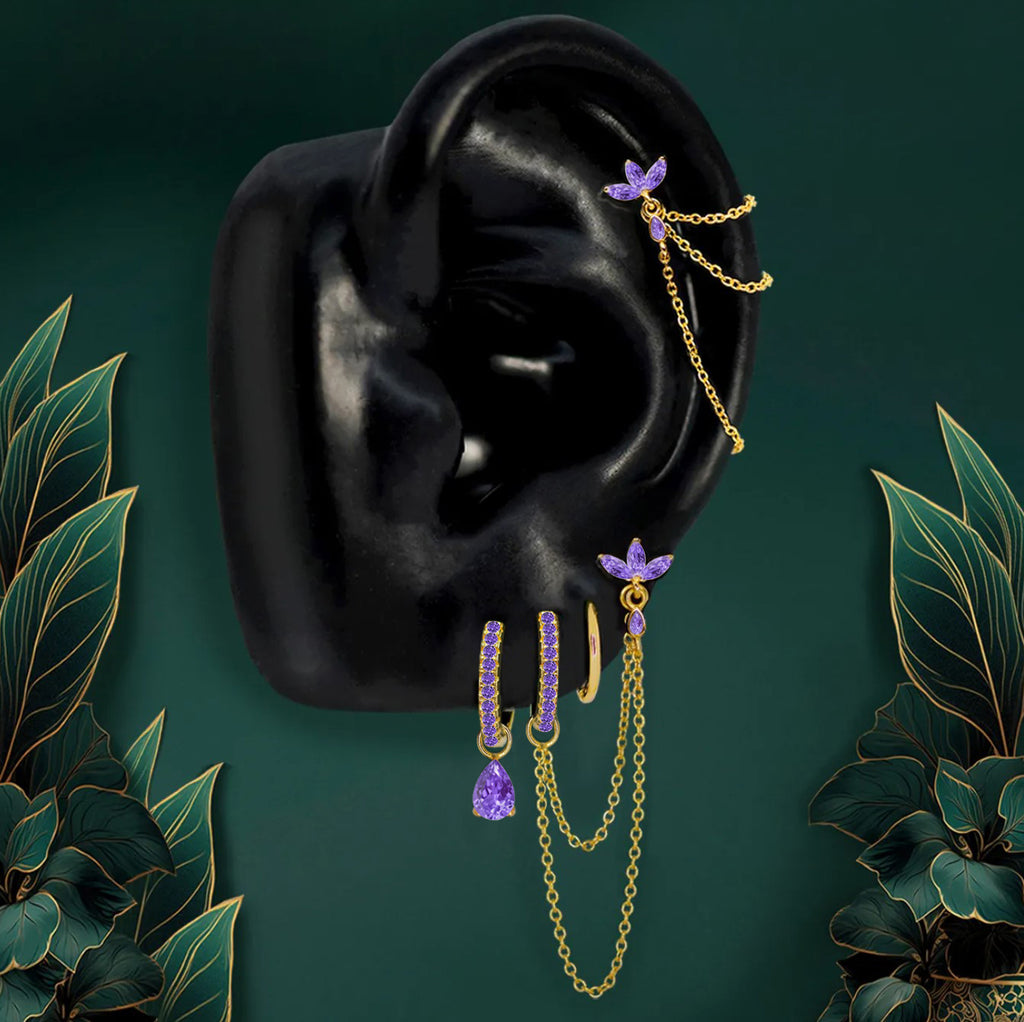 Dainty purple earrings styled in an elegant earring stack with gold hoops and studs.